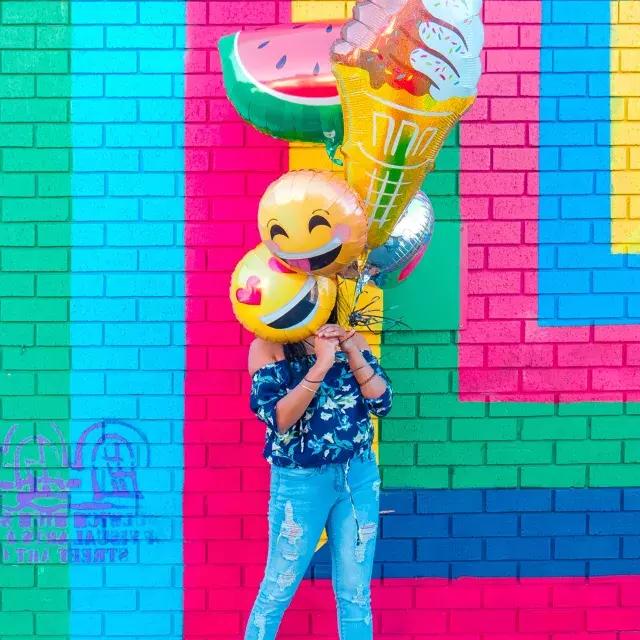 一个女孩在一幅彩色壁画前用气球庆祝她的生日.